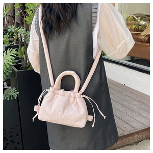 Blush pink quilted drawstring backpack worn by a model in a natural outdoor setting