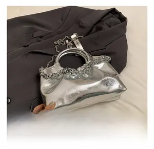 Detail view of silver mirror PU handbag featuring pleated design and metal ring handle