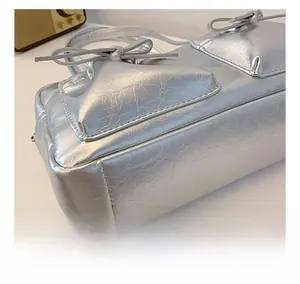 Détail du sac à main en cuir PU argenté montrant la texture craquelée et les nœuds