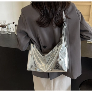 Detail of silver metallic crescent bag featuring unique cracked texture and butterfly buckles