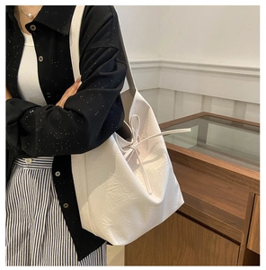 Detail of creamy white PU leather tote bag featuring side drawstring bow and soft texture