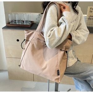 Detail of apricot canvas tote bag with black drawstring and brand woven label