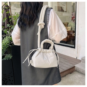 Close-up of minimalist cream white puffed crossbody bag with pleated texture and soft drawstring