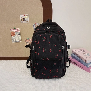 Détail du sac à dos en velours noir avec imprimés cerises et poche avant