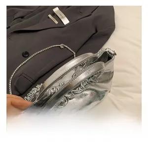 Detail of silver metallic PU bag with ruffled handle and elegant chain shoulder strap