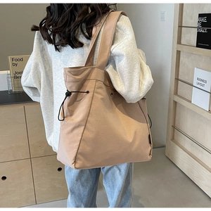 Detail of a large canvas drawstring tote bag in apricot with adjustable straps