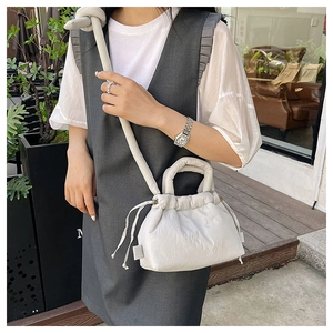 Detail of off-white puffy cloud bag with drawstring closure and soft nylon texture