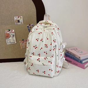 Détail de la texture velours côtelé et motifs cerises rouges sur sac à dos crème