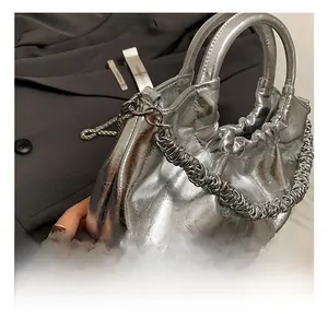 Detail view of silver pleated PU leather handbag with metallic chain strap and side texture