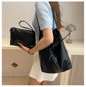 Detail of black PU leather tote bag set with decorative tassel and matching zipper pouch