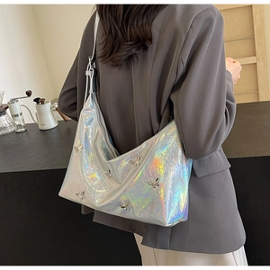 Detail view of silver holographic hobo bag with 3D metallic butterfly accents on model