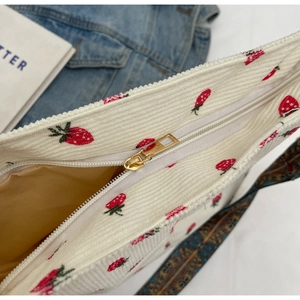 Close-up of white corduroy tote bag with strawberry embroidery and woven strap