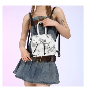 Detail of a white mini PU backpack with black butterfly prints worn by a model