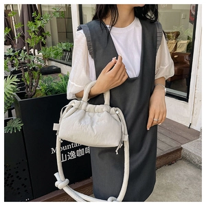 Detail showing soft quilted light grey crossbody bag with knotted rope strap for women