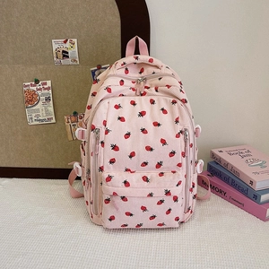 Détail du sac à dos en velours côtelé rose avec imprimés fraises et plusieurs poches zippées