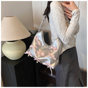 Silver crescent hobo bag with pink bows and pearl charms shown on person shoulder