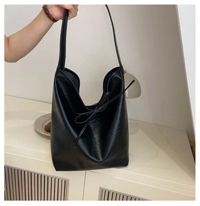 Detail view of the black pleated PU leather hobo bag with an elegant bow accent