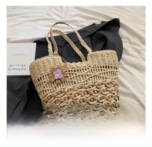 Detail of woven straw tote bag with brown wave pattern and purple flower charm