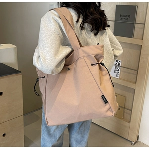 Detail view of pink canvas tote bag with drawstring closure and brand label shown on model