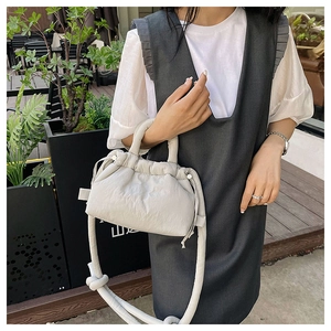 Detailed close-up of light grey quilted polyester crossbody bag with drawstring design