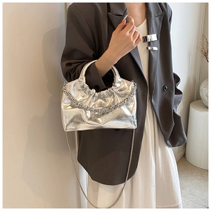 Detail of silver metallic pleated handbag with curved metal handle and chain strap