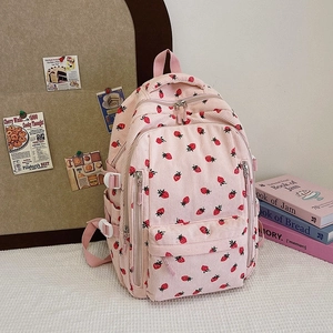 Détail d'un sac à dos en velours côtelé rose clair à imprimé fraise et boucle blanche