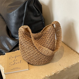 Sac seau en paille tressée d'été avec motif ajouré posé sur un socle en pierre sobre