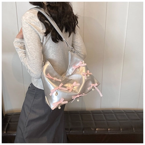 Silver PU leather hobo bag with pink satin bow and pearl detail shown on shoulder