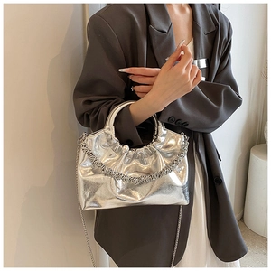 Detail of silver metallic pleated handbag featuring a delicate metal chain and soft cloud shape