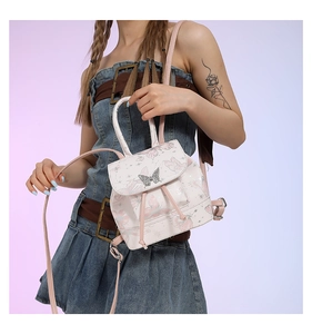 Detail of a mini butterfly backpack with glitter pink straps and a silver charm pendant