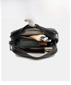 Detail view of black lychee leather crossbody bag with multi-zipper layers and large storage