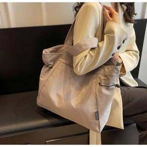 Detail view of nylon tote bag with drawstring design and side brand label shown by model