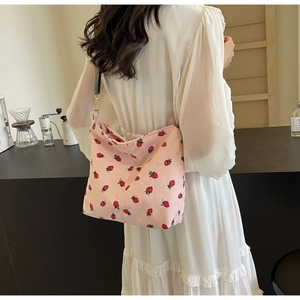 Detail of pink corduroy tote bag with strawberry print and decorative wide shoulder strap