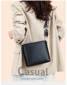 Detail of black pebbled leather crossbody bag with wide geometric pattern strap
