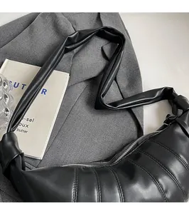 Detailed close-up of a black PU leather croissant bag with segmented stitching and knotted strap