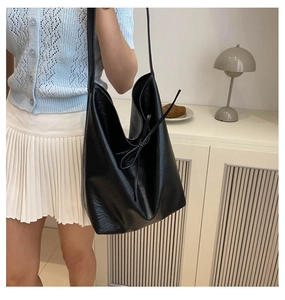 Detail of a large black PU leather hobo bag with drawstring tie and soft texture
