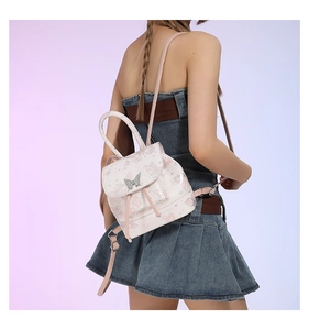 Detail of light pink mini backpack featuring butterfly patterns and a crystal buckle