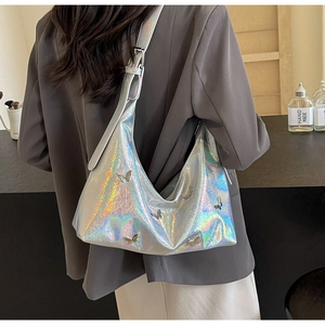 Detail view of holograph silver crossbody bag with metal butterfly accents and wide strap