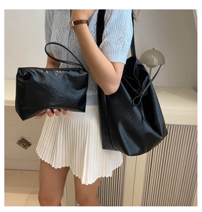 Detail of black pleated PU leather tote bag set featuring stylish side bow knot accents