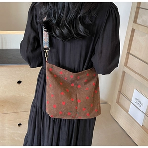 Detail of brown corduroy bucket bag with strawberry patterns and vintage woven strap