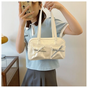 Détails des nœuds argentés et poches plissées sur le sac à main en similicuir blanc cassé