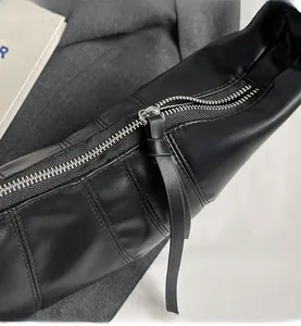 Close-up of black PU leather bag featuring a smooth silver metal zipper and long puller