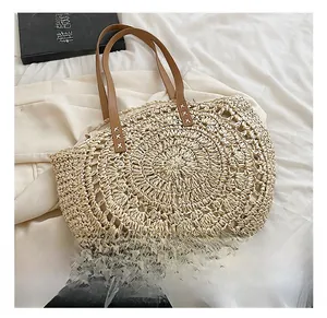 Detail of handwoven beige straw tote with brown leather handle and cross-stitch accents