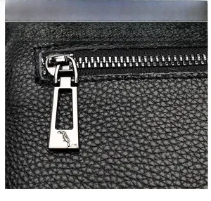 Close-up of silver metal zipper with bird logo on black lychee grain leather handbag