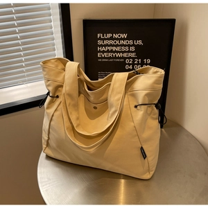 Minimalist cream canvas tote bag with black drawstring details and dual shoulder straps