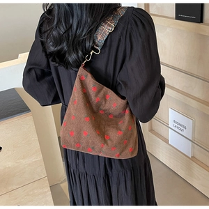 Detail of strawberry embroidery on brown corduroy tote with ethnic style strap