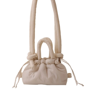 Cream quilted puffer crossbody bag with drawstring closure and knotted handles
