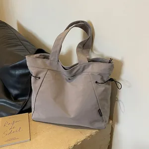 Minimalist large canvas tote bag with adjustable drawstrings on a stone tabletop
