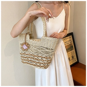 Close-up of handmade woven straw tote with wavy pattern and purple flower charm