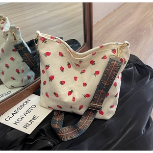 Detail of strawberry corduroy bucket bag with vintage geometric patterned wide strap
